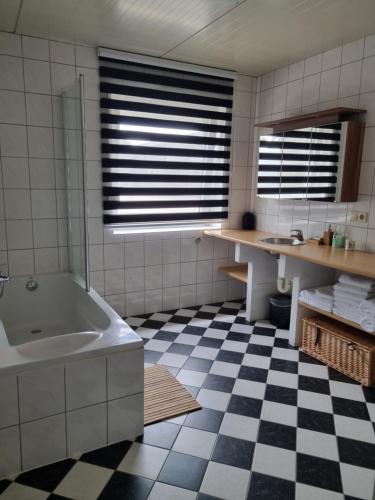 a bathroom with a tub and a checkered floor at Vakantiewoning Schouwenberg in Swalmen