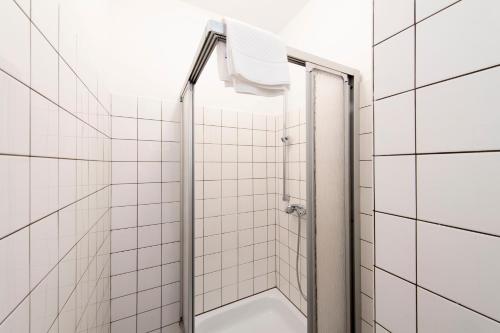 La salle de bains est pourvue d'une douche et de carrelage blanc. dans l'établissement Working Loft Emmerich - 8 box spring beds, à Emmerich