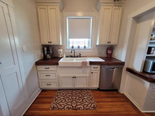 a kitchen with white cabinets and a sink and a rug at Holland House - Historic and Sophisticated in Alpine