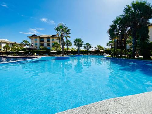 duży błękitny basen z palmami i budynkami w obiekcie Resort VG SUN por Be My Guest! w mieście Caucaia