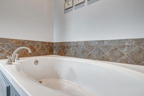 a white bath tub in a bathroom with tiles at Beautiful Front Row Views - Tiki Bar - Playground in Bolivar Peninsula