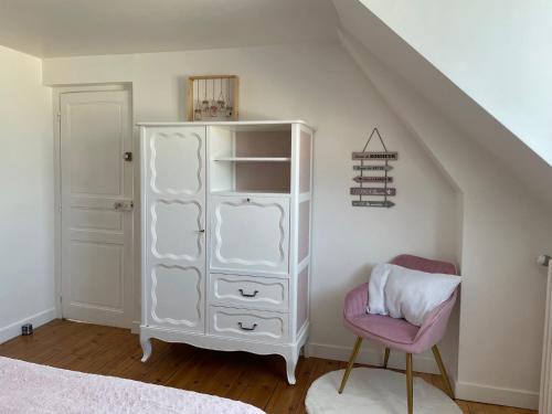- une chambre avec une armoire blanche et une chaise rose dans l'établissement Le Char'Mans, cocon suréquipé en centre ville, au Mans