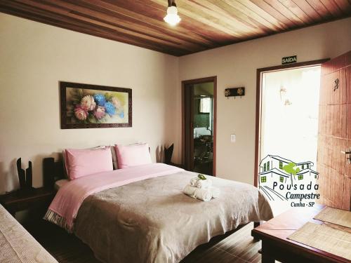 a bedroom with a large bed with a stuffed animal on it at Pousada Campestre Cunha-SP in Cunha