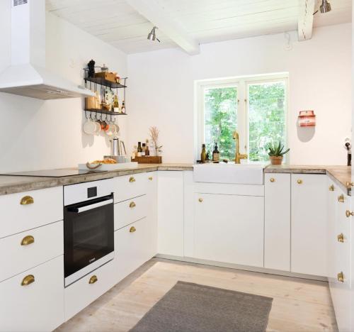 eine weiße Küche mit weißen Schränken und einem Fenster in der Unterkunft Bokis - Modern Forest Cottage in Brösarp