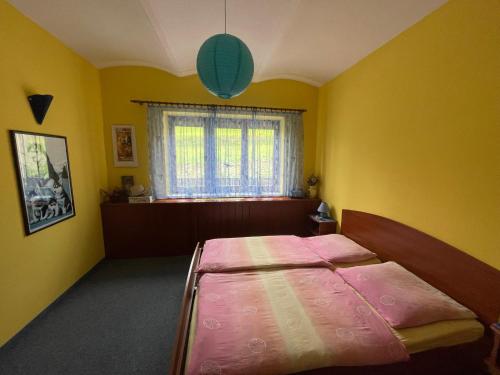 um quarto com uma cama num quarto amarelo em Ubytování v Krkonoších, rodinný apartmán Peklíčko em Horní Lánov
