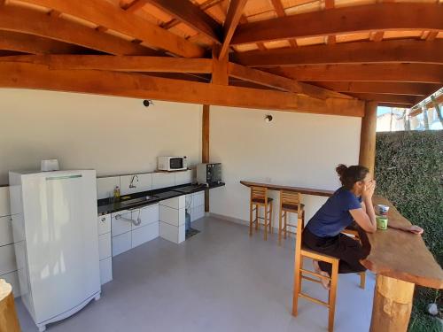 烏巴圖巴的住宿－Caminho da areia，坐在厨房桌子上的女人