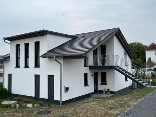 una casa blanca con techo negro en Ferienwohnung Ederseeblick en Waldeck