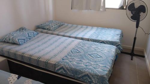 two twin beds in a room with a fan at Apartamento à beira mar Praia de Unamar in Cabo Frio