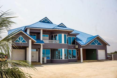 une grande maison avec un toit bleu dans l'établissement Moven Paradise, à Accra
