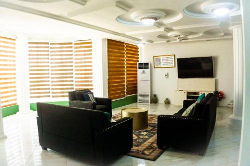 Una sala de estar con dos sillas y un televisor de pantalla plana. en Moven Paradise, en Accra