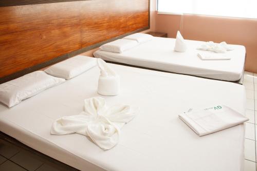 two beds with white sheets and a white bow on them at GV Hotel - Tacloban in Tacloban