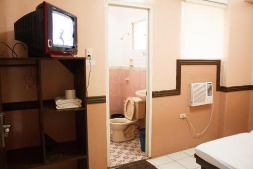 a bathroom with a toilet and a tv in it at GV Hotel - Tacloban in Tacloban