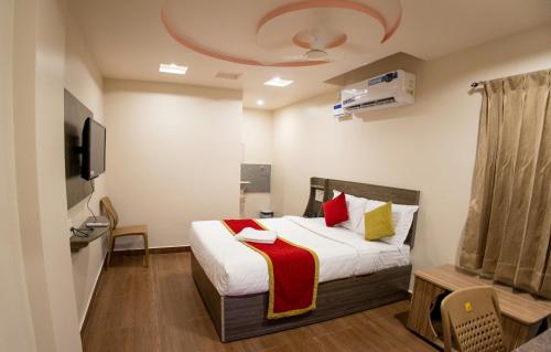 ティルパティにあるDLR GRANDのベッドとテレビ付きのホテルルーム