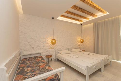 a white bedroom with two beds and a chair at Kallithea Hotel in Agia Anna Naxos