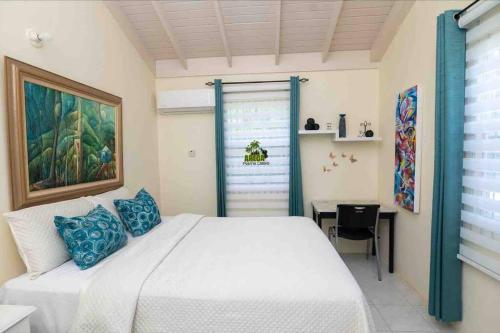 a bedroom with a white bed with blue pillows at ArecaPalmsOasis King Bed Near Dunns River Falls in Mammee Bay