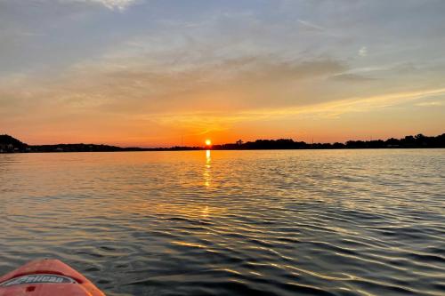 a boat on a body of water with a sunset at Steps to Lake! Charming Cabin Pool Access and Decks in Granbury