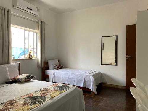 Habitación con 2 camas, espejo y ventana en Barra Porto - Suítes & Kitnets, en Salvador