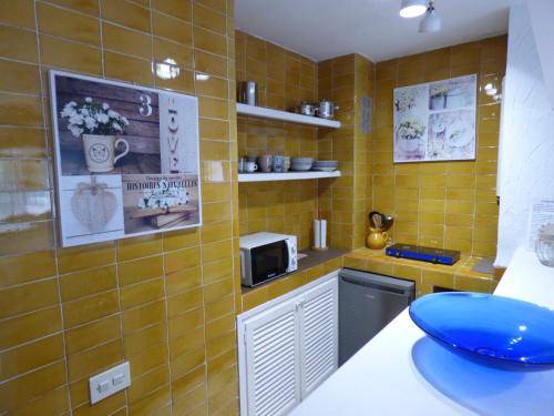 uma pequena cozinha com paredes em azulejos amarelos e um micro-ondas em Rigel Es Pujols em Es Pujols