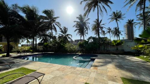 a swimming pool with palm trees in a yard at Vila Saguaro in Trairi
