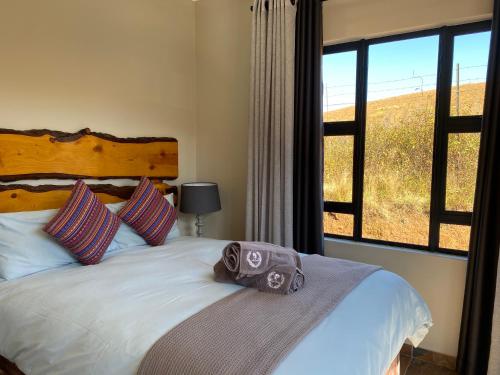 a bedroom with a bed and a large window at Lake Glencairn in Underberg