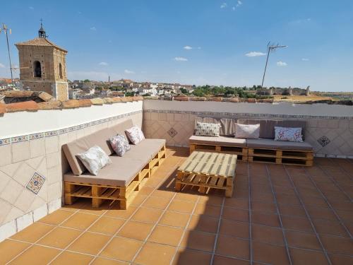 a patio with couches and tables on a roof at Casa La Plazuelilla in Chinchón