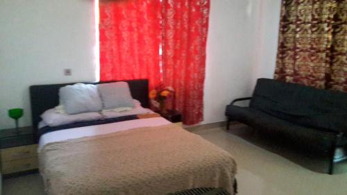 a bedroom with a bed and a couch and a red curtain at Hayben serviced apartments in Accra