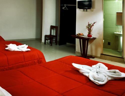 una camera da letto con un letto rosso e asciugamani di Hotel Montecristo ad Arequipa
