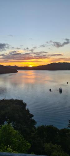 a sunset on a lake with boats in the water at Boho Hill Apartment - Great Barrier Island Escape in Port Fitzroy