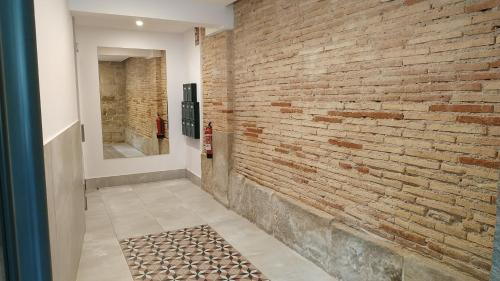 pasillo con pared de ladrillo y espejo en Casa Ochoa en Logroño