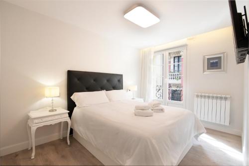 a white bedroom with a large white bed and a window at Casa Ochoa in Logroño