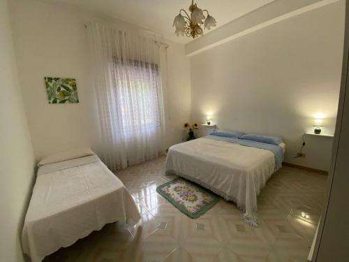 a white bedroom with two beds and a window at La casa di Mussiù in Salemi