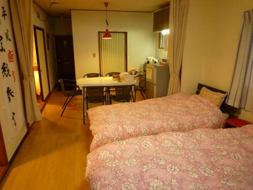 a room with two beds and a table and a kitchen at Futami Terrace C in Ise