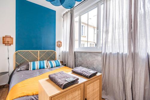Schlafzimmer mit einem Bett mit blauen Wänden und einem Fenster in der Unterkunft Au Cœur de Reims - Orchidée in Reims