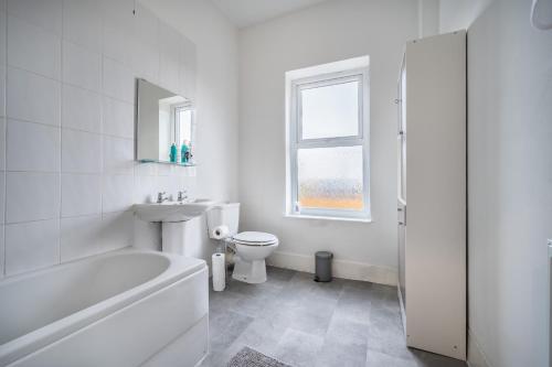 a white bathroom with a tub and a toilet and a sink at Modern spacious 2 bedroom house in Leigh Self Service in Leigh