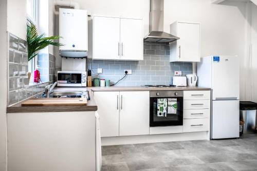 a kitchen with white cabinets and a sink at Modern Spacious 2 Bedroom House in Leigh, Free Parking in Leigh