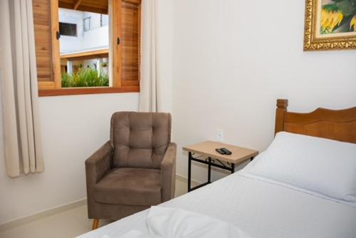 a bedroom with a bed and a chair and a window at Pousada Pôr do Sol in Cunha