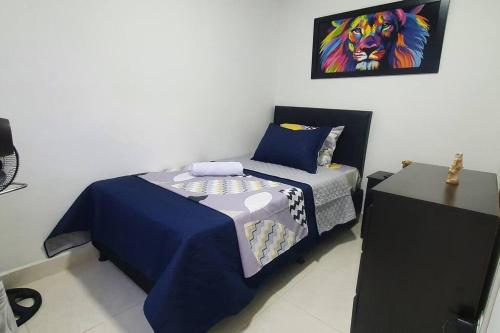 a bedroom with a bed with a painting on the wall at central apartamento al lado del polideportivo sur de envigado in Envigado