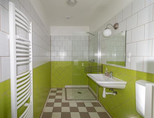 a green and white bathroom with a sink and a mirror at Villa Deco Parádsasvár in Parádsasvár