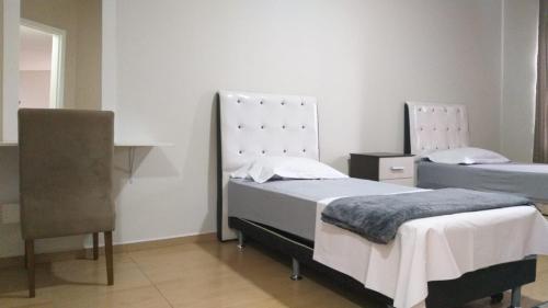 a bedroom with two beds and a desk and a chair at HAPPY HOSPEDAGENS in Cascavel
