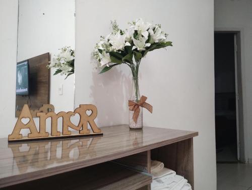 a vase of white flowers sitting on a table at HAPPY HOSPEDAGENS in Cascavel