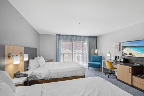 um quarto de hotel com duas camas e uma secretária e uma televisão em Hotel Avisa Downtown em Morro Bay