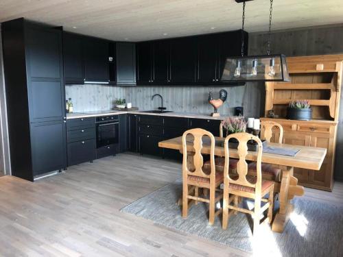 una cocina con armarios negros y una mesa y sillas de madera. en Beitotind sentralt på Beitostølen en Beitostøl