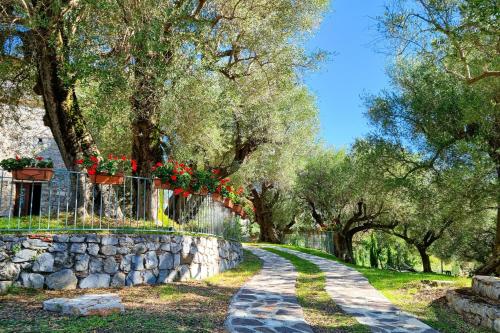 un chemin en pierre avec des fleurs rouges sur une clôture et des arbres dans l'établissement Pie' d'Ulivo, à Bosco
