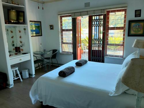 a bedroom with a white bed with two black towels on it at Double Room - Robberg in Plettenberg Bay