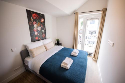 1 dormitorio con 1 cama grande y 2 toallas. en Happily 2 Bedroom Serviced Apartment 75m2 -NB306H-, en Róterdam