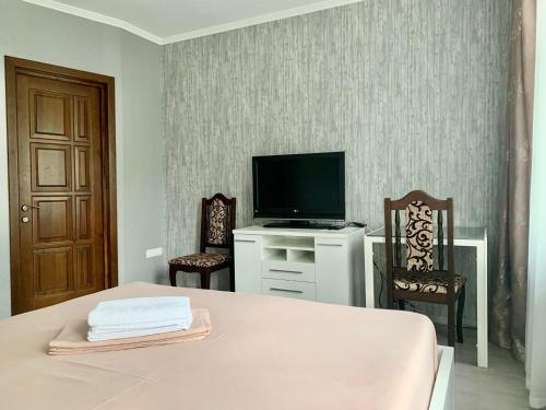 een kamer met een bed en een televisie en twee stoelen bij Мини-гостиница Три Коня in Pereiaslav-Khmelnytskyi