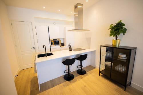 a kitchen with a counter with stools and a sink at Earnestly 1 Bedroom Serviced Apartment 54m2 -NB306E- in Rotterdam