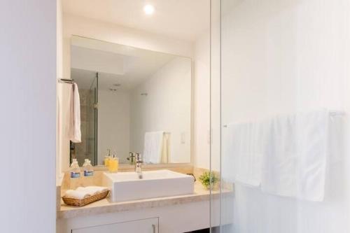 een badkamer met een witte wastafel en een spiegel bij Esquina mágica en el mejor edificio del Centro Histórico in Mexico-Stad