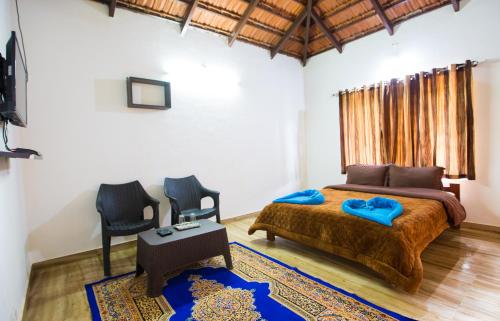 a bedroom with a large bed and two chairs at The Nest bettathur, Coorg in Madikeri