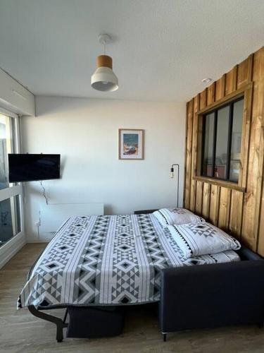 une chambre avec un lit et une télévision dans l'établissement Appartement face à l’Océan, à Lacanau